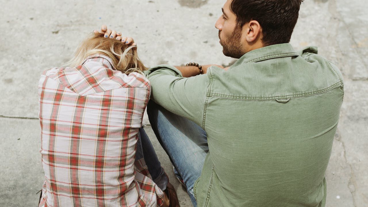man and woman sitting on kerb