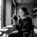 Woman sitting in a cafe, looking at her smartphone with a coffee cup on the table beside her.